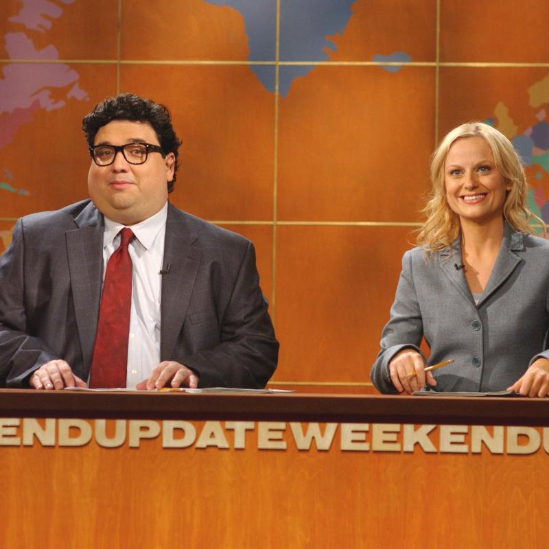 Saturday Night Live (SNL) players Horatio Sanz and Amy Poehler sitting at the anchor desk during a segment of Weekend Update