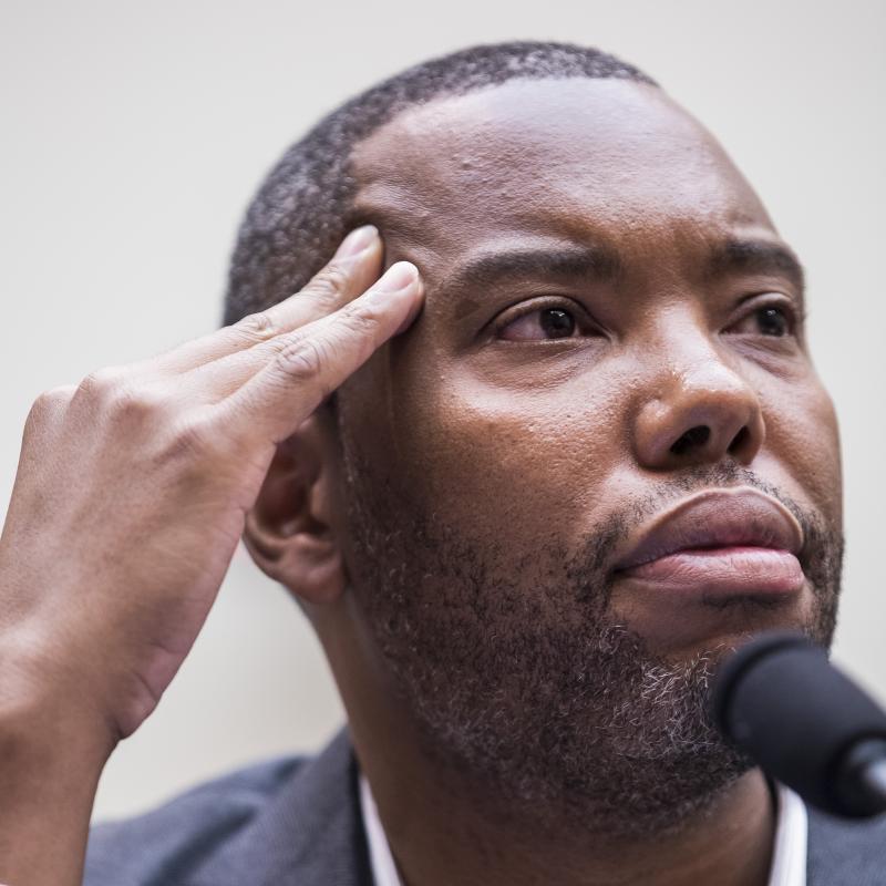 Writer Ta-Nehisi Coates looks pensive while sitting at a microphone