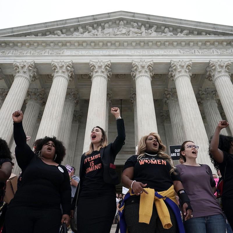 Female protestors stand with raised firsts in front of the Supreme Court building in Washington, DC>