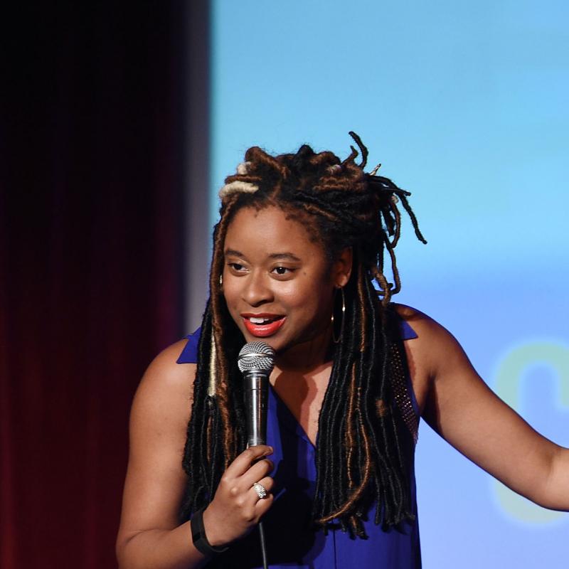 Comedian Phoebe Robinson speaks into a mic on stage