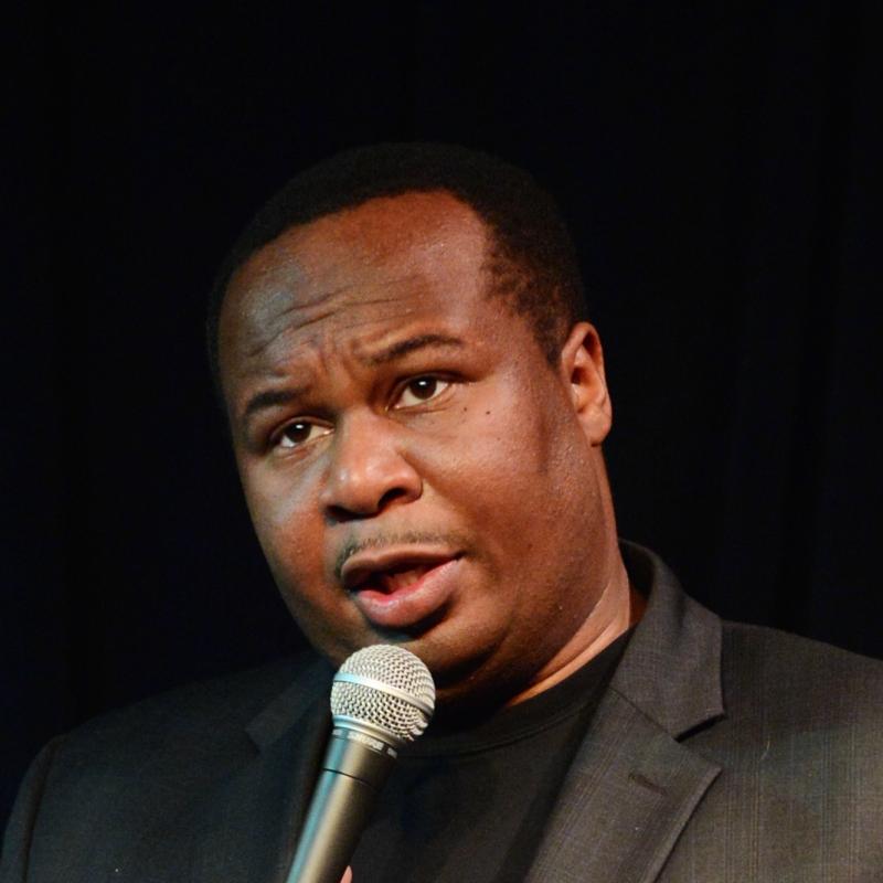 Comedian Roy Wood Jr speaks into a mic on stage