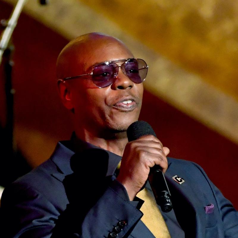 Comedian Dave Chappelle laughs on stage